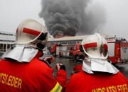 To brandmænd på job står med ryggen til og evaluerer situationen